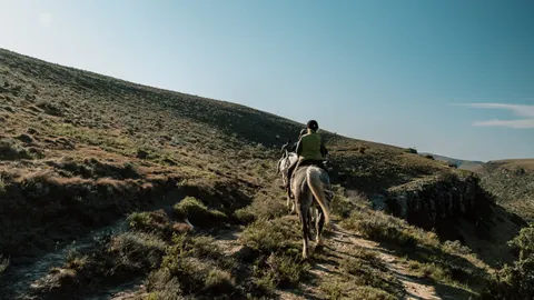 Riders riding across a rocky hillside