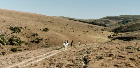 Riders travelling across a broad mountain valley