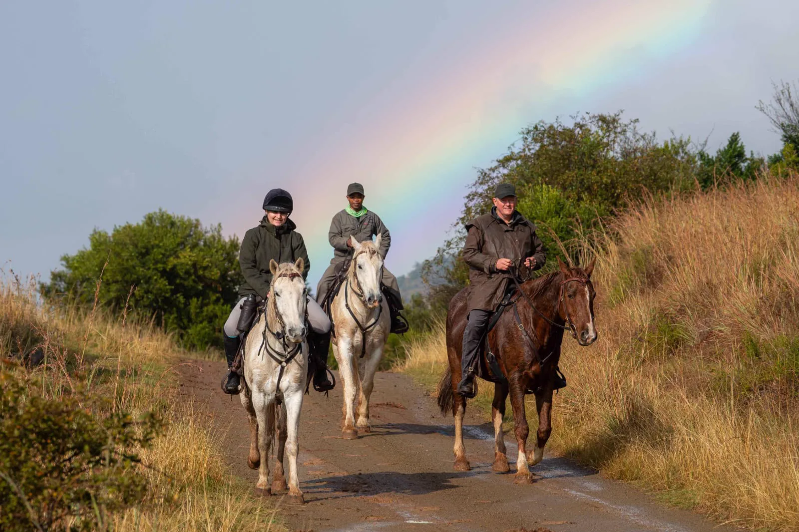 Riders following a scenic trail beneath a rainbow in the Mankazana Valley